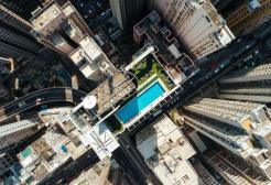 Aerial view of a city with tall skyscrapers and a rooftop swimming pool