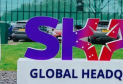 A female student in a blazer outside a sign for SKAO