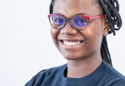 A female student turned to the left smiling in front of a white background