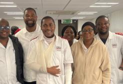 A group of nursing students stood together smiling at the camera. One student at the front has their arm in a cast