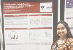 Student Aveen Sabir at a conference stood next to a poster