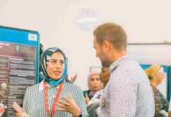 A researcher presents a poster of her research to a colleague