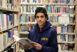 Student with an open book in the Clifford Whitworth Library, University of Salford