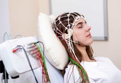Woman lying in bed wearing EEG equipment 