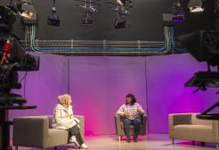 Four students in the TV studio. Two students sat in the presenting seats and another two students operating the cameras.