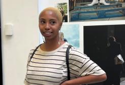 A female student stood in New Adelphi foyer in front of a screen with her hand on her hip looking to the side of the camera