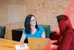 Two people seated at a table have a discussion 