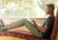 A person studies on a laptop against a window