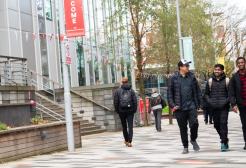 Three male students walking through Peel Park campus next to the New Adelphi