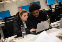 A male and female student working on a laptop