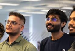 Four students, three male and one female, looking up at a screen to the left of the camera