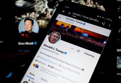 A smartphone screen displays Donald Trump's X account with Elon Musk in the background