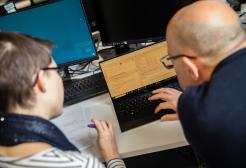 Student and academic working on a laptop together