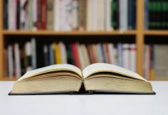 An open book stands on a table within a library