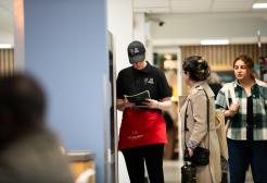 Catering staff standing with a customer in the library cafe