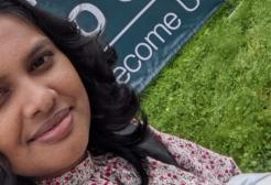 A female student taking a selfie in front of the Welcome to Salford sign