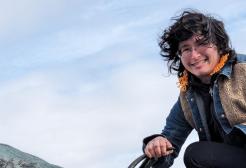 A student with curly hair crouching on a horse statue