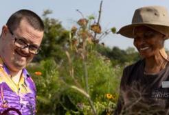 A man and a woman enjoy the community garden in sunshine