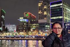 A student on a bridge with the MediaCity skyline behind her