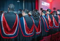 Group of standing graduates in front of a stage