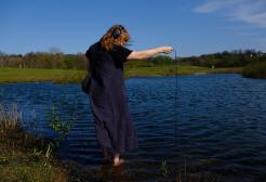 Hayley Suviste holding a microphone by a lead submerged in water at Kersal Wetlands