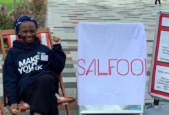 Nafisah sat on a deck chair next to a sign for Salfood