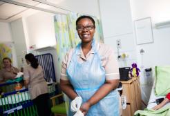 Female Nursing Associate apprentice putting on gloves on a simulation hospital ward