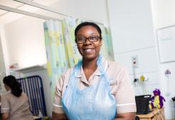 Nursing associate apprentice putting on gloves in a simulated ward environment