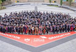 Graduates posing for a group photograph outside the The Lowry Building in Salford Quays