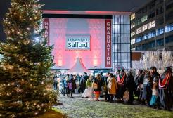 Guests and graduates entering Maxwell Hall with a christmas tree outside