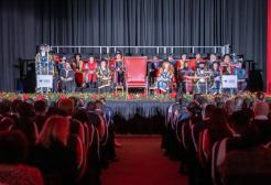 Chancellor's Procession is seated on stage in Maxwell Hall during a graduation ceremony