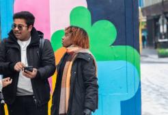 Three international students looking at a phone in Stevenson Square