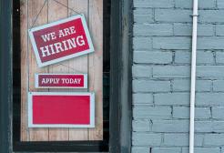 A sign reading 'We are Hiring' hangs in a window