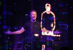 A man performs next to a holographic figure