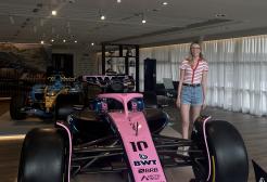 A woman stands next to a pink Formula One car