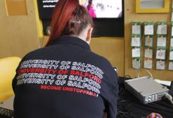 University staff member working at a laptop wearing 'Become Unstoppable' branded clothing
