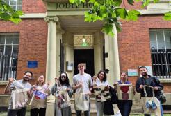 A group of people smiling and holding their DIY tote bags after a tote bag workshop.