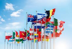 A line of national flags in front of a sunny sky