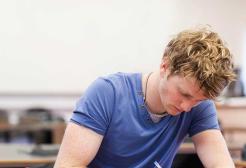 A young white male student sitting at a table studying