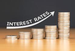 Increasing coin stacks with lettering to indicate raising interest rates