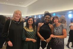 Four women are pictured at an awards ceremony, they smile at the camera