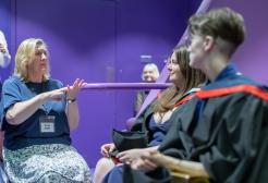 A British Sign Language Interpreter faces two graduates in the theatre. 