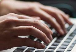 Close-up of a person’s hands typing on a laptop keyboard