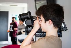 A young boy holds a video camera 