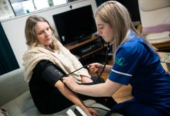 Nurse taking a patient's blood pressure in their home