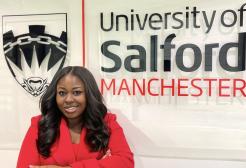 Maudlyn Akosua Awuku in front of the University of Salford logo