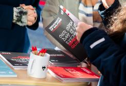 A member of staff flicking through the Open Day guide at the Open Day check-in desk
