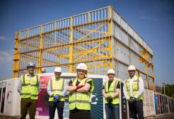 Figures stand in front of the Acoustics building steel frame