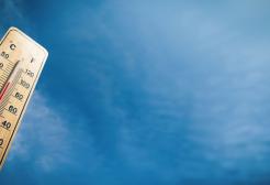 An upwards angle of a rising thermometer in front of a blue sky