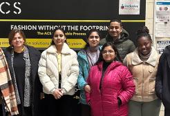 Group of fashion business and marketing students stood in front of a sign for ACS (Advanced Clothing Solutions)